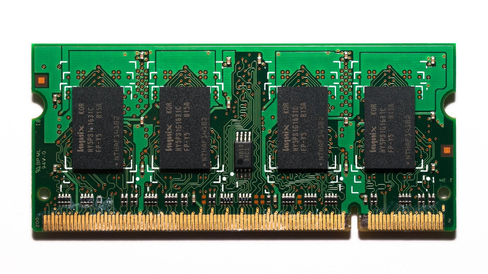 Close-up of a high-performance memory chip module on a circuit board with data center server racks blurred in the background.