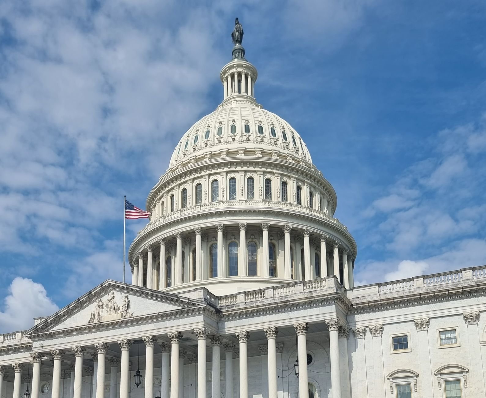 US Capitol dome in the foreground with a blurred background of a modern data center server room, symbolizing government involvement in AI infrastructure