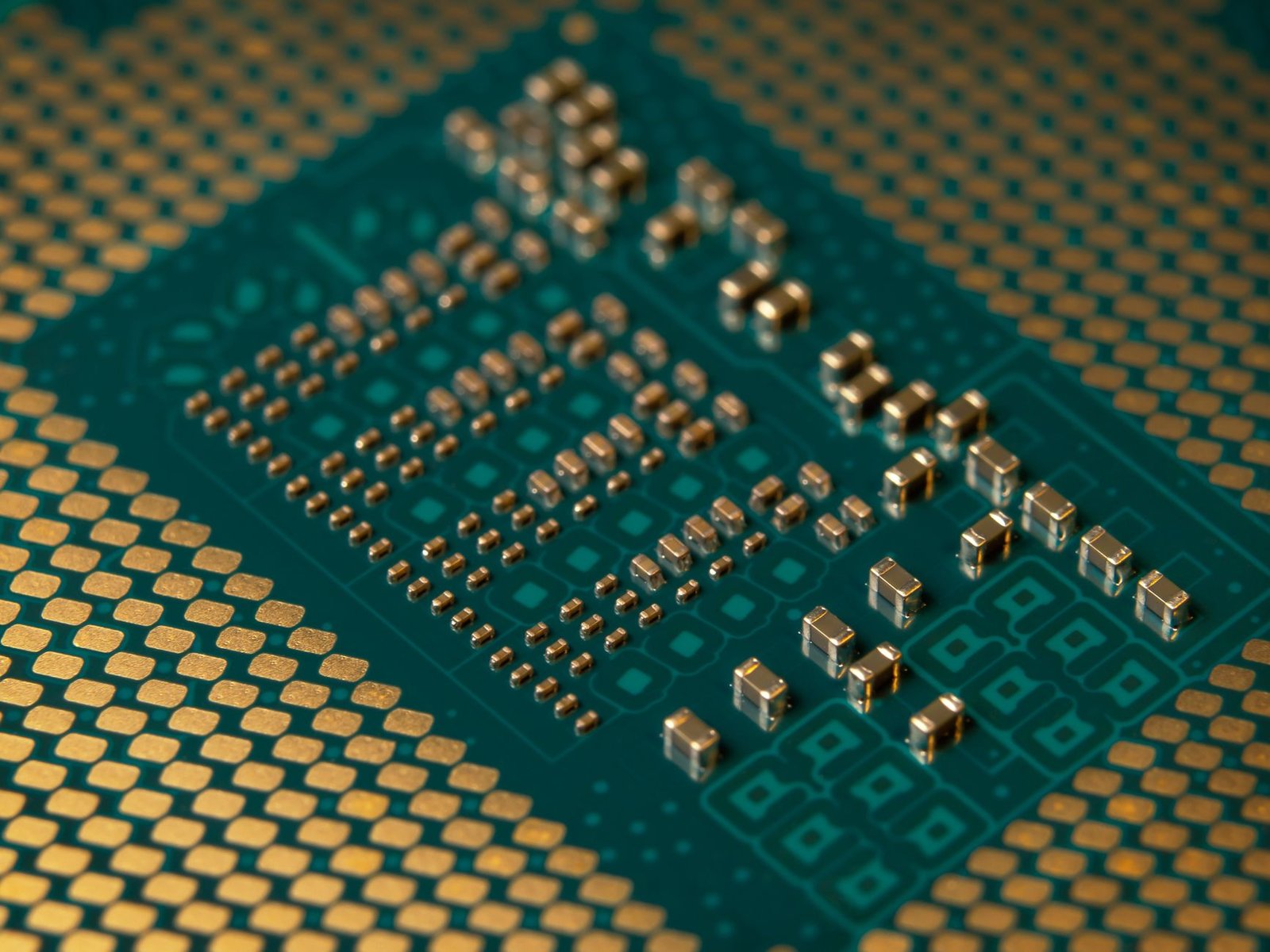Close-up of a silicon chip on a circuit board with metallic traces and capacitors visible