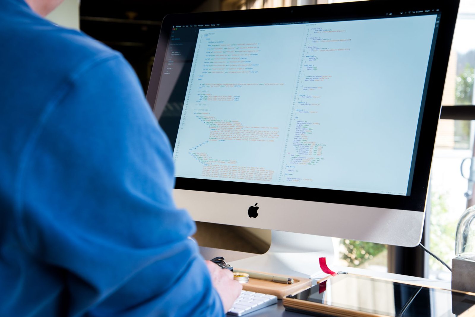A backend software developer working on a laptop displaying code with AI-assisted suggestions, symbolizing integration of Llama 4 into enterprise workflows.