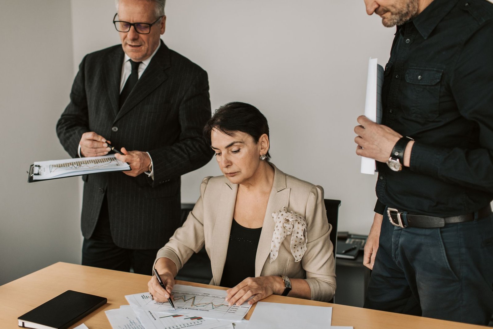 Two business professionals in a glass-walled conference room reviewing AI strategy documents and charts on a tablet