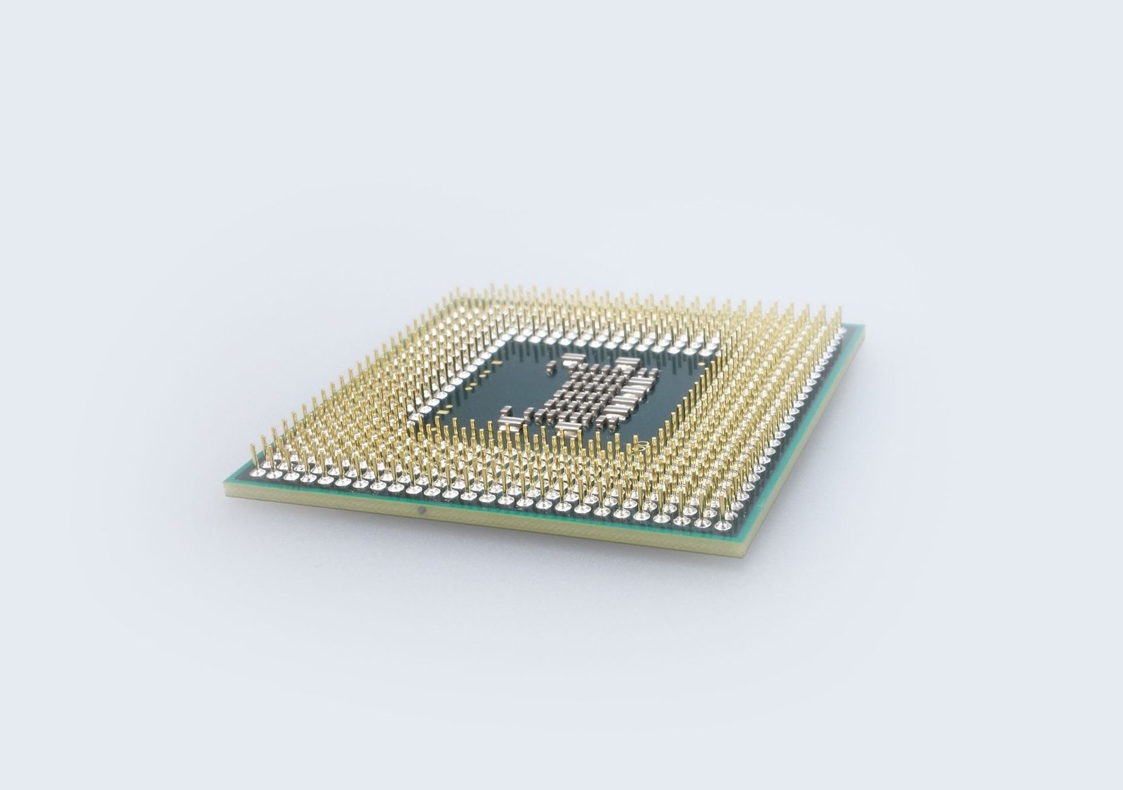 Close-up of a silicon photonic chip on a circuit board with fiber optic cables connected, glowing blue light