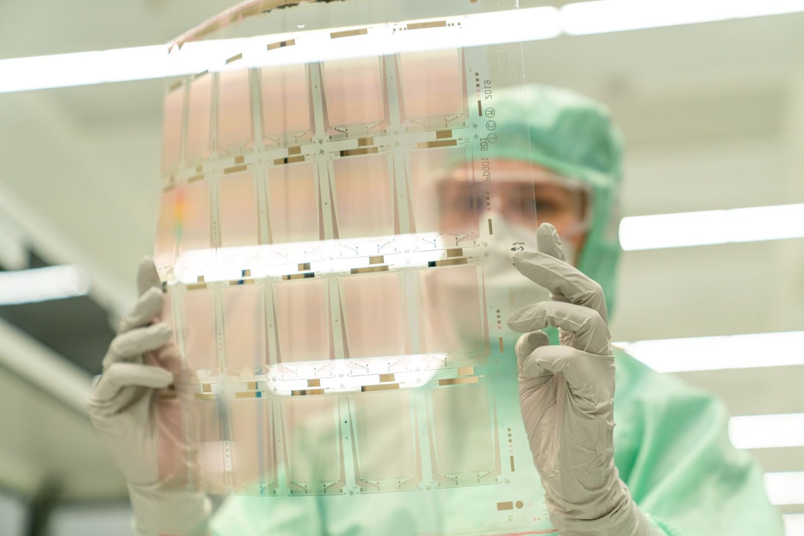 Engineer holding a transparent glass substrate panel used for next-generation chip packaging in a lab